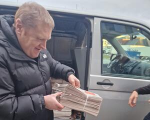 Mann løfter aviser ut av bil 
